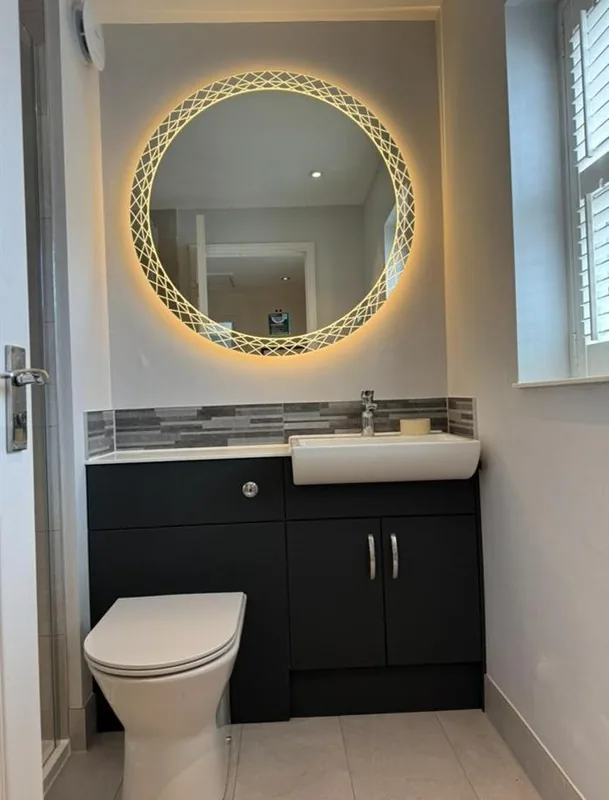 Backlit decorative round mirror above a navy vanity