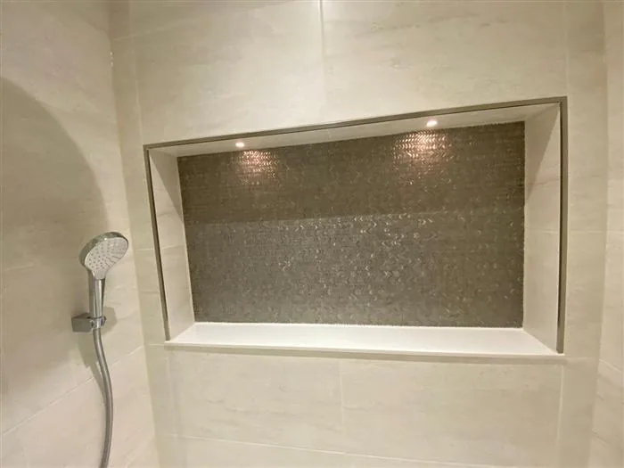 Tiled shower niche with mosaic detail and inset spotlights